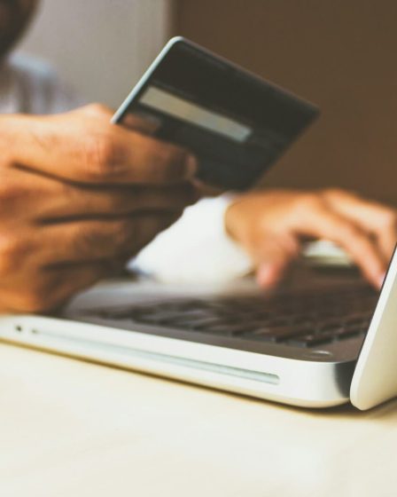 person using laptop computer holding card