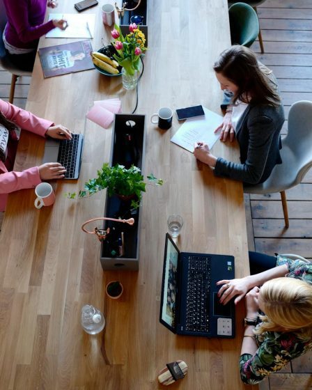 Overhead view of diverse women professionals working in a modern office setting, fostering collaboration and teamwork.